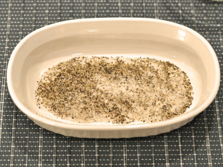 salt, pepper, celery salt, sugar mixed up in a white bowl on blue placemat