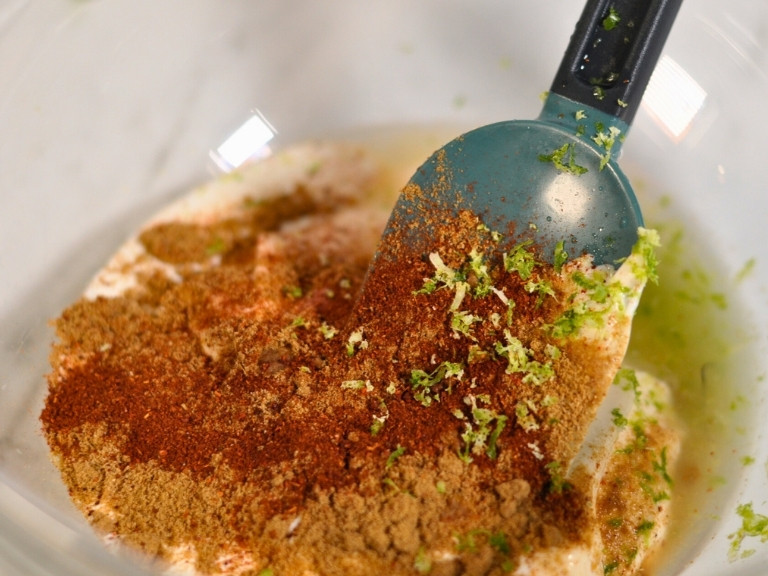 elote pasts salad ingredients in glass bowl with mixing spoon