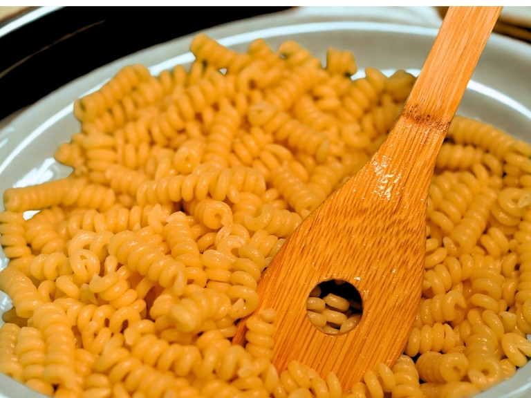 cooked fusilli Bucati pasta on plate with wooden spoon