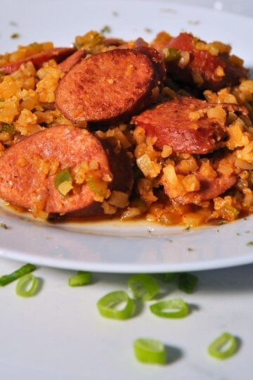 sausage, cauliflower rice, and diced bell pepper on white plate