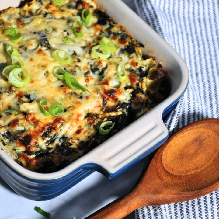 smoked spinach artichoke dip in baking dish with wooden spoon