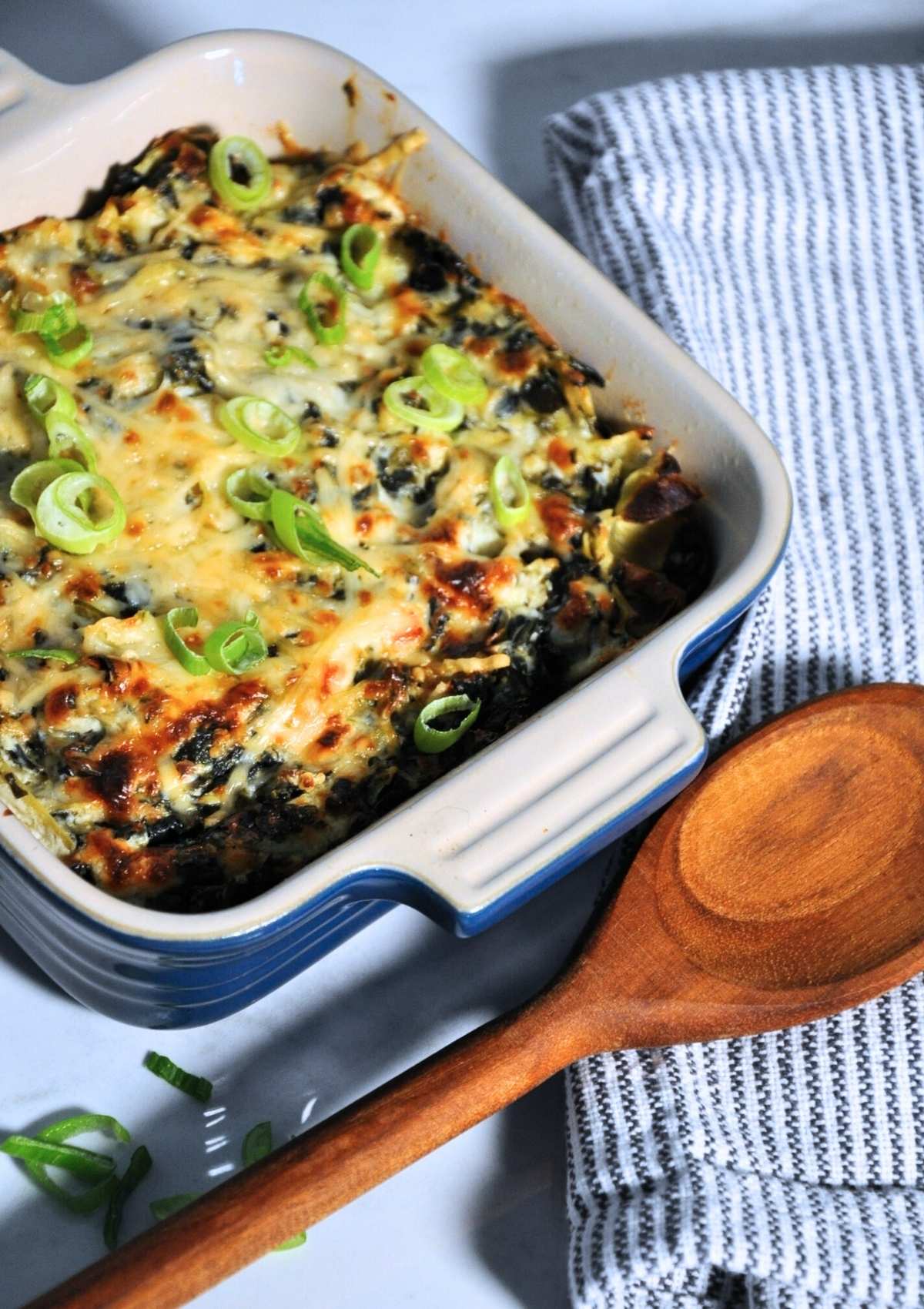 smoked spinach artichoke dip in baking dish with wooden spoon