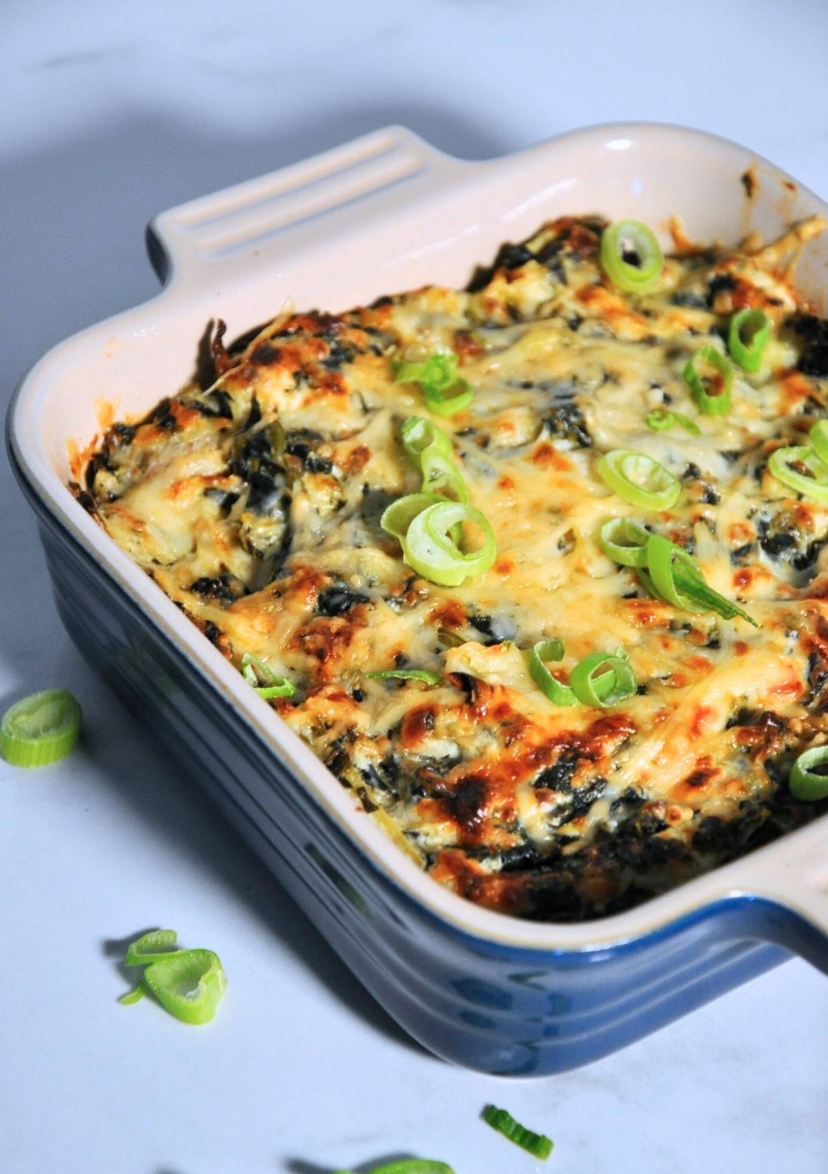 smoked spinach artichoke dip in baking dish with green onions
