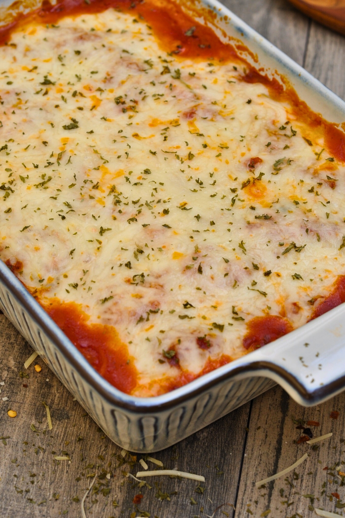 beef and spinach lasagna in white and blue baking dish on table