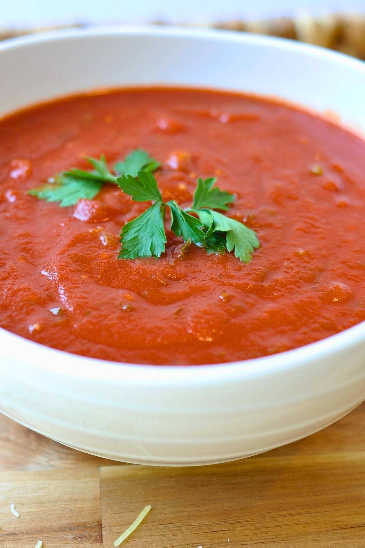 red marinara sauce in white bowl with green parsley on top