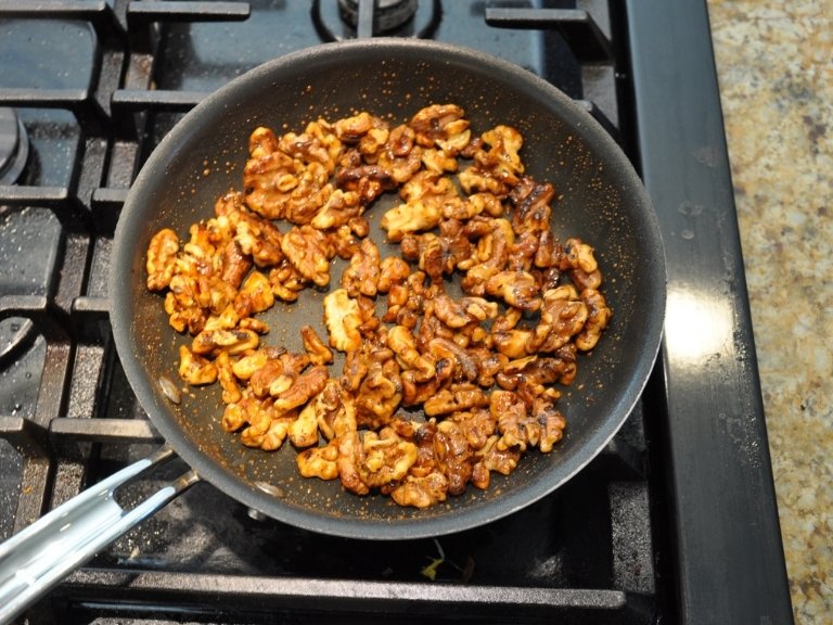 honey glazed walnuts in a non stick pan on a gas range stove