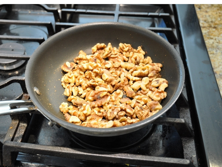 raw walnuts in a non stick pan on a gas range stove